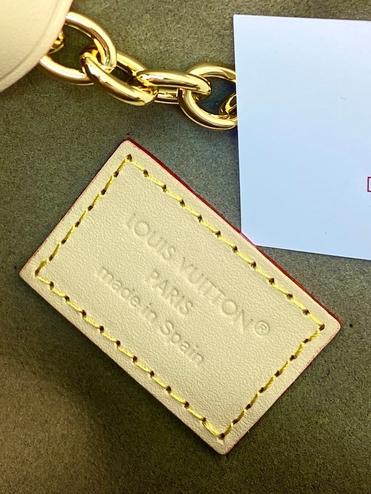 Small handbag leather logo patch with gold embossed branding and yellow stitching