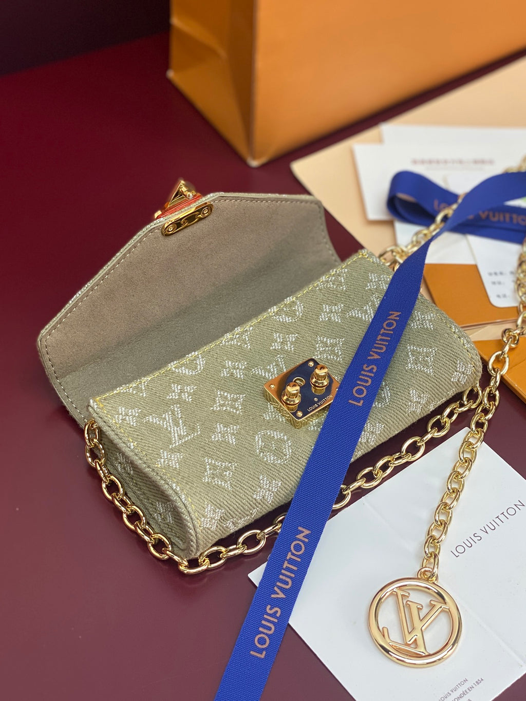 Gray-green monogram mini handbag with gold chain strap and flap lock, tan lining visible