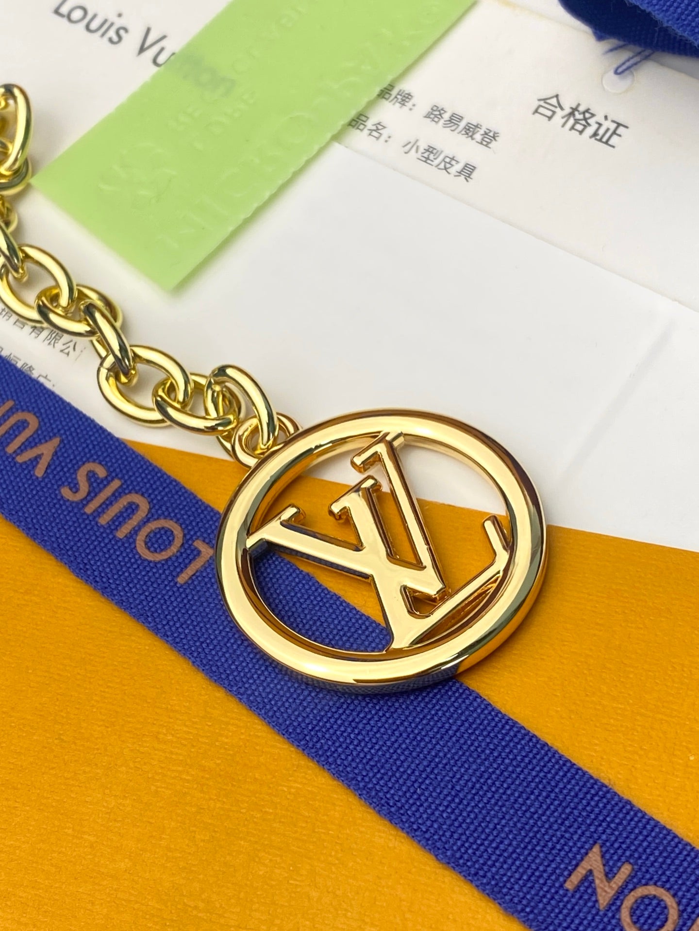 Small handbag key-ring charm with gold emblem on blue strap