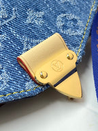 Louis Vuitton small bag with gold logo hardware on blue denim