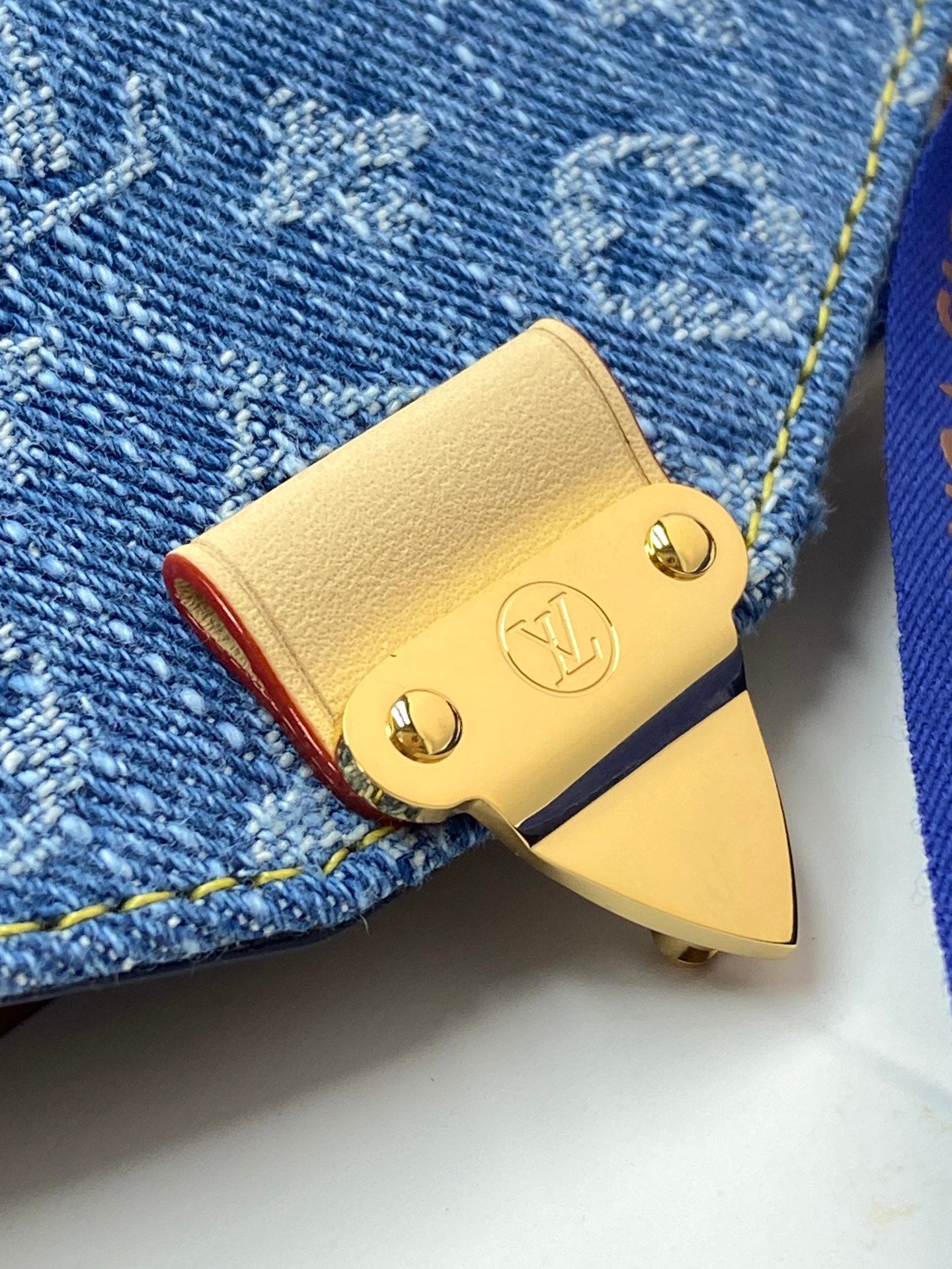 Louis Vuitton bag with light yellow leather flap and gold logo studs on denim