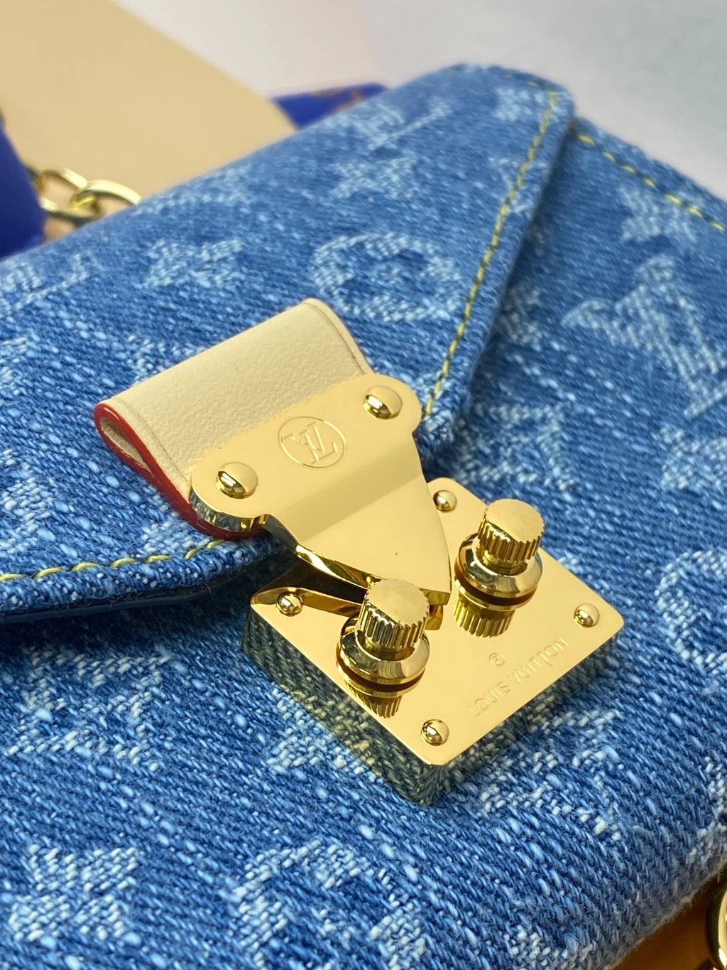 Close-up of gold flap lock on blue monogram canvas mini bag