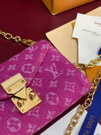 Louis Vuitton small bag corner detail with gold flap hardware on purple monogram canvas