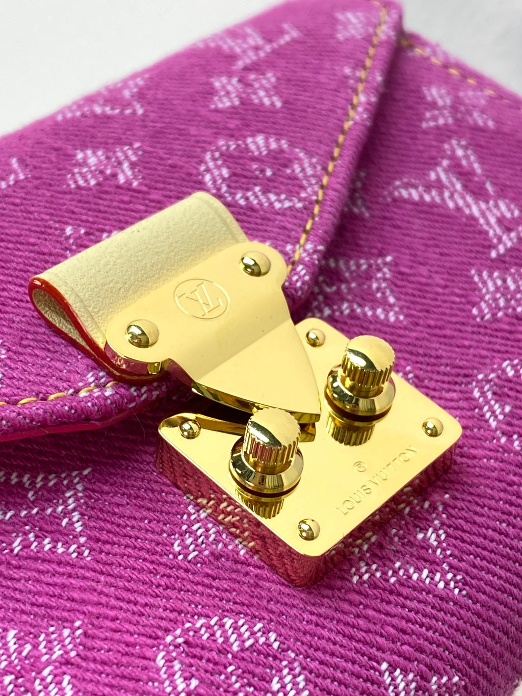 Louis Vuitton small bag close-up of gold turn-lock hardware on purple monogram canvas