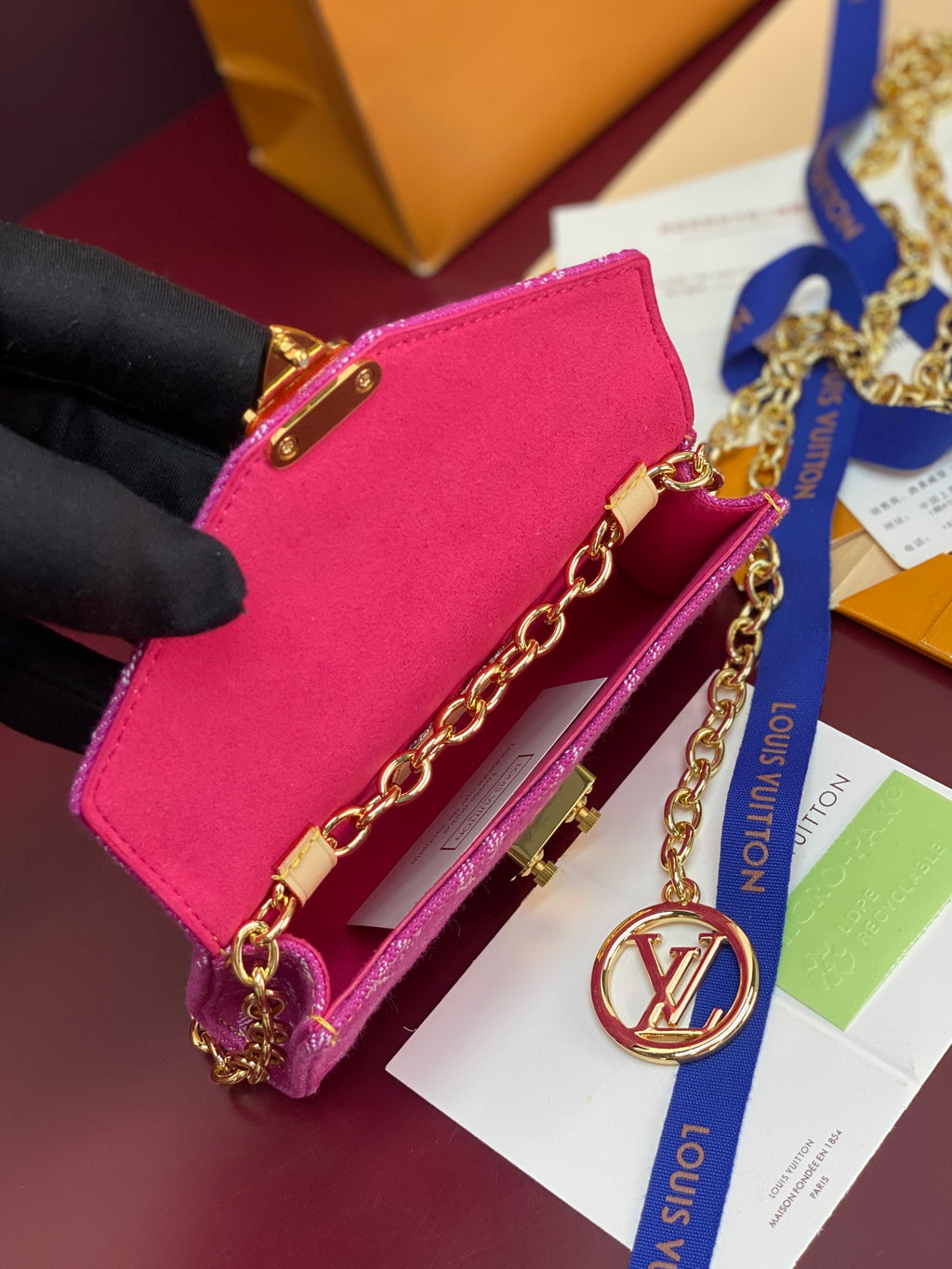 Hot pink mini flap bag with gold chain strap and round emblem charm