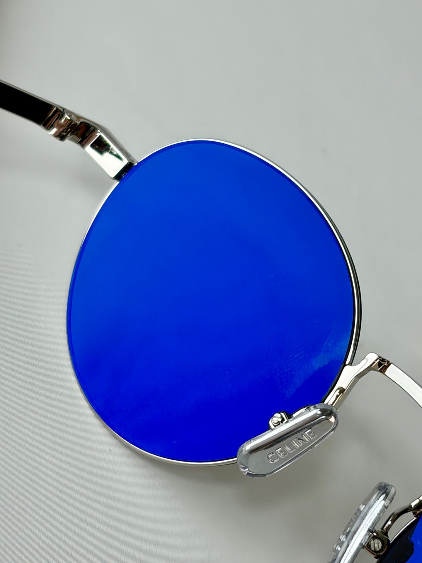 Celine round glasses close-up with blue-tinted lenses and reflective metal frame