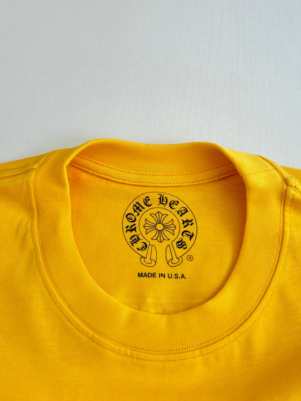 Yellow T-shirt crew neck label with round crest and “Made in U.S.A.” text