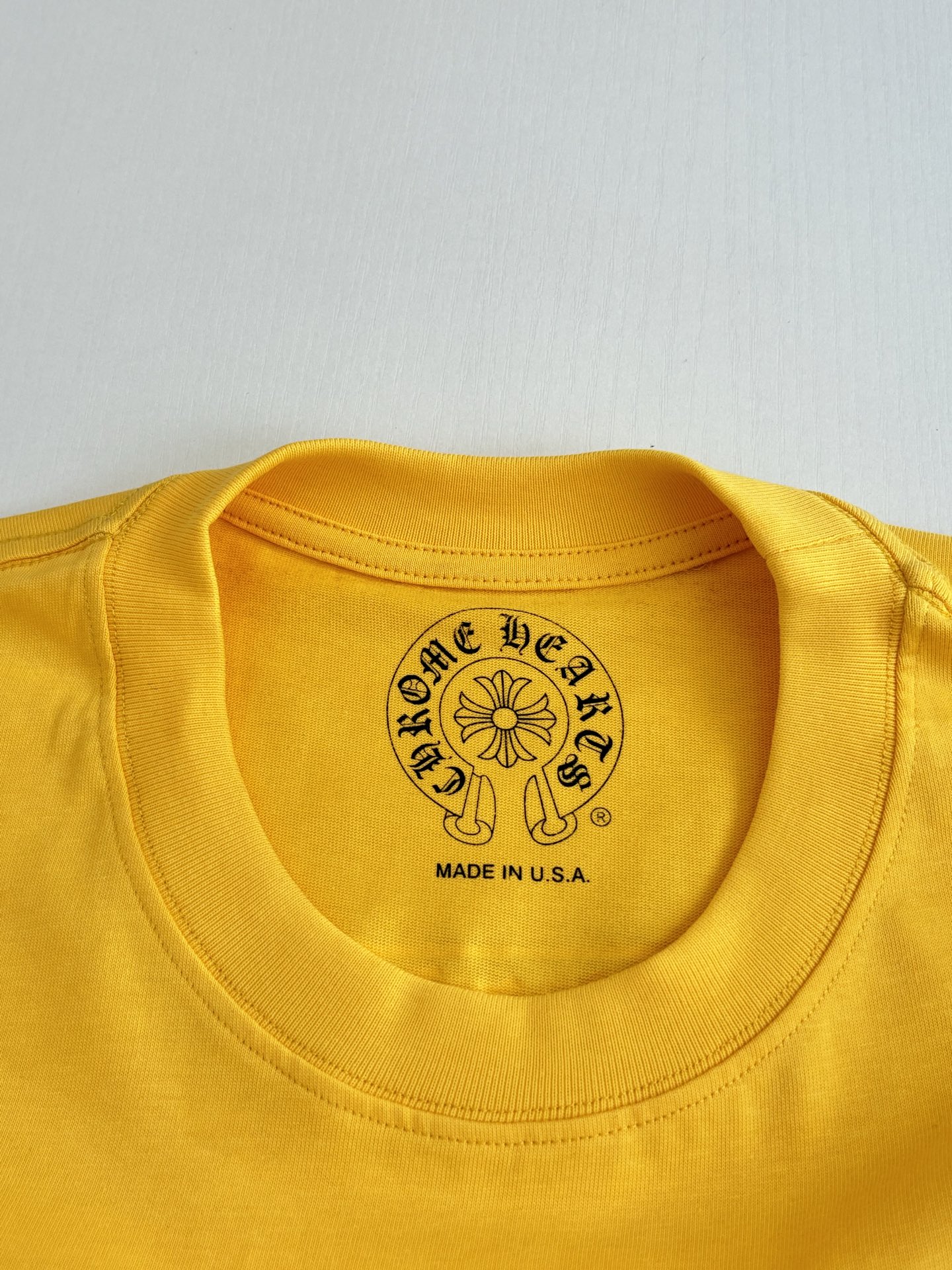 Yellow T-shirt crew neck label with round crest and “Made in U.S.A.” text