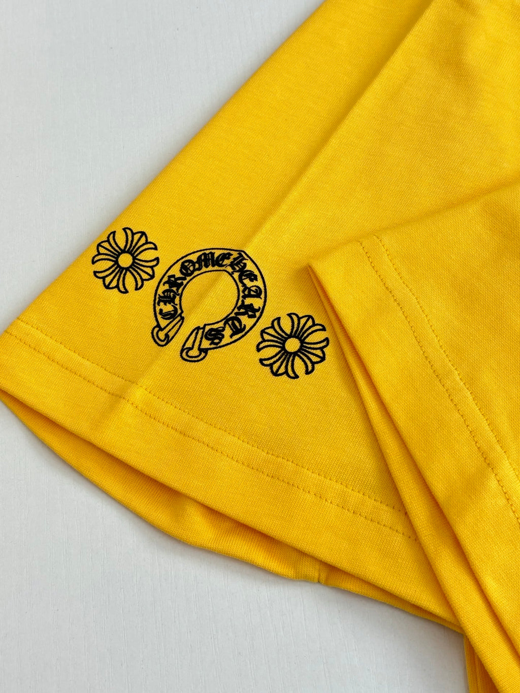 Yellow T-shirt sleeve with small horse-and-flower graphic