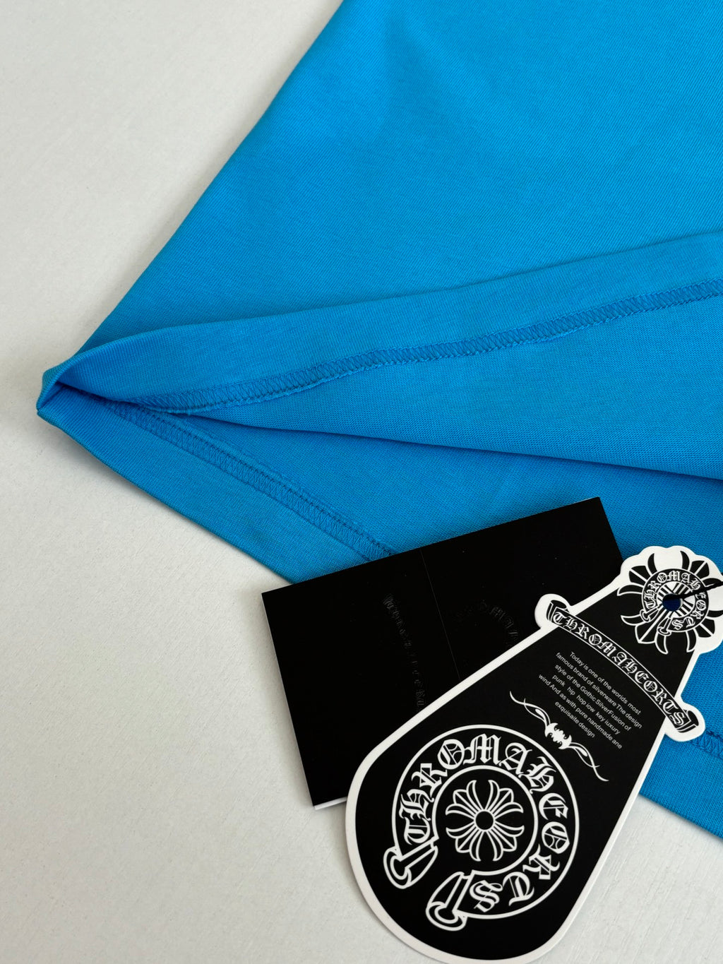 Folded blue T-shirt fabric with side seam stitching and hang tag