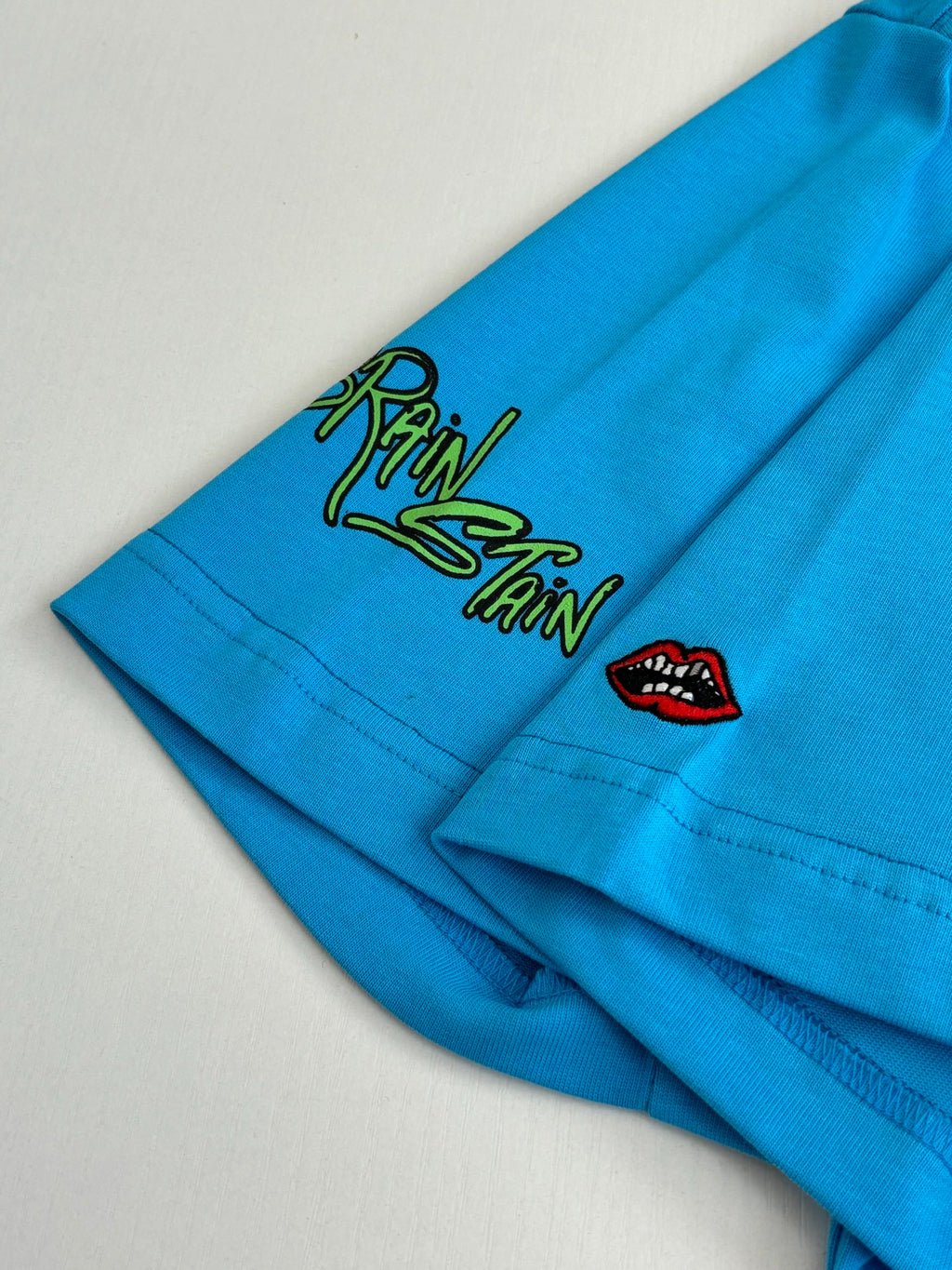 Blue T-shirt sleeve with small green doodle graphic and red lip icon