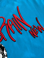 Blue T-shirt close-up of red “BRAIN NEW” graphic lettering