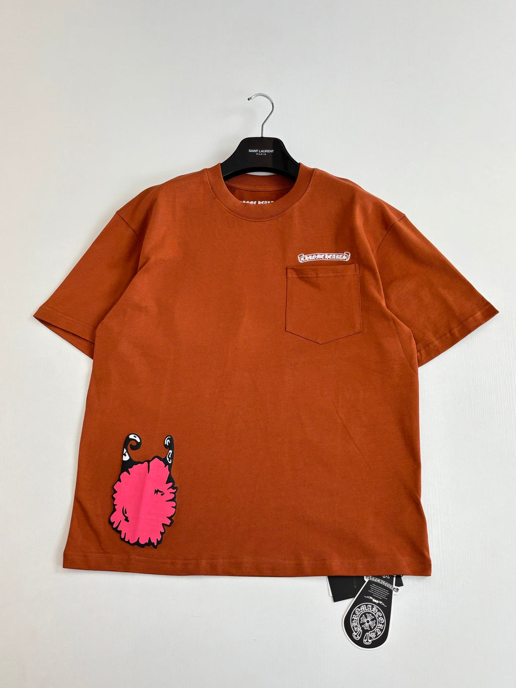 Orange short-sleeve T-shirt with front pocket and large pink character graphic