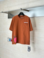 Orange short-sleeve T-shirt with front pocket and small character graphic