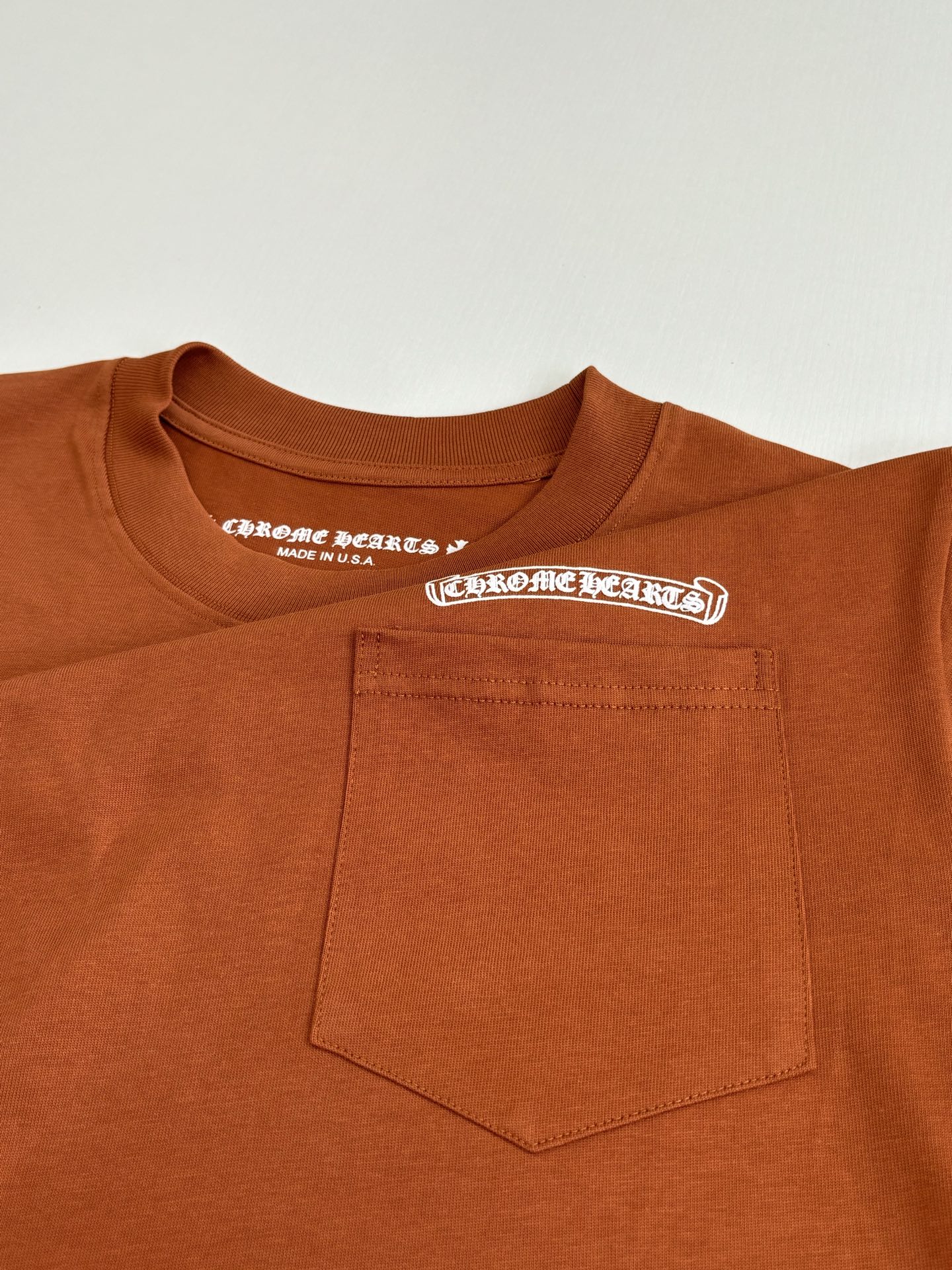 Orange T-shirt front pocket with small printed logo label detail
