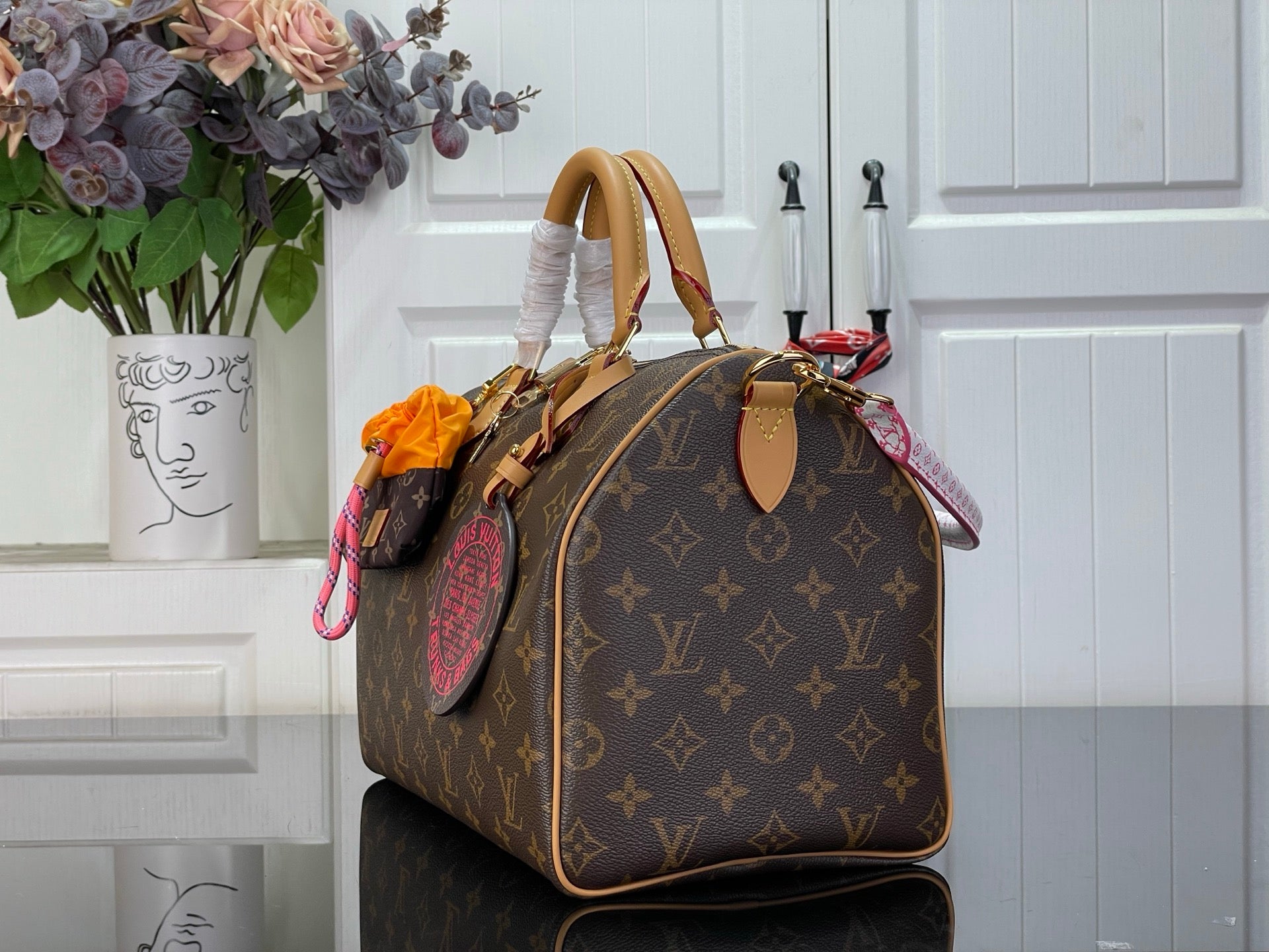 Louis Vuitton monogram handbag with tan handles and pink ribbon detail at side