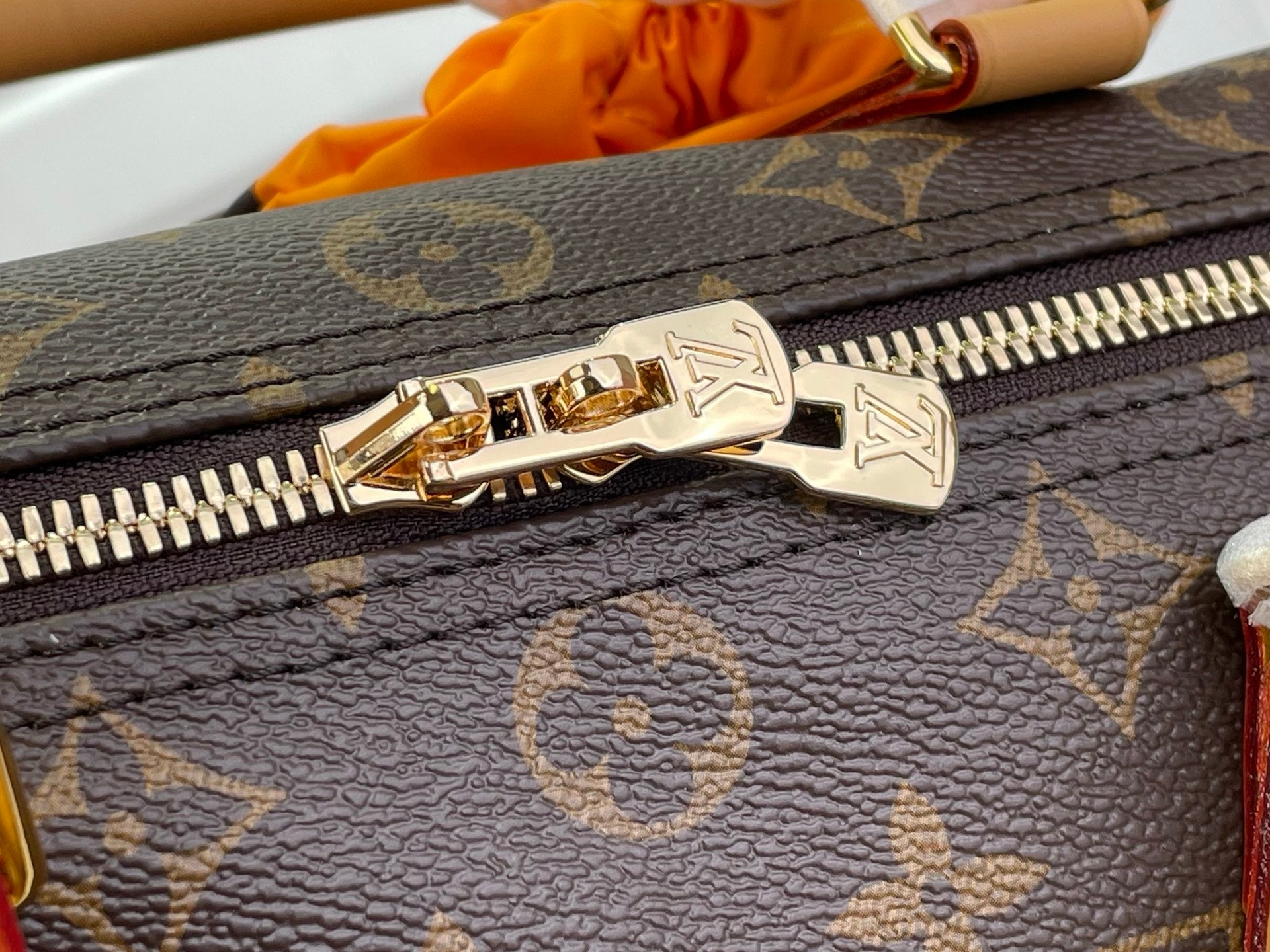 Louis Vuitton monogram bag zipper close-up on dark brown canvas
