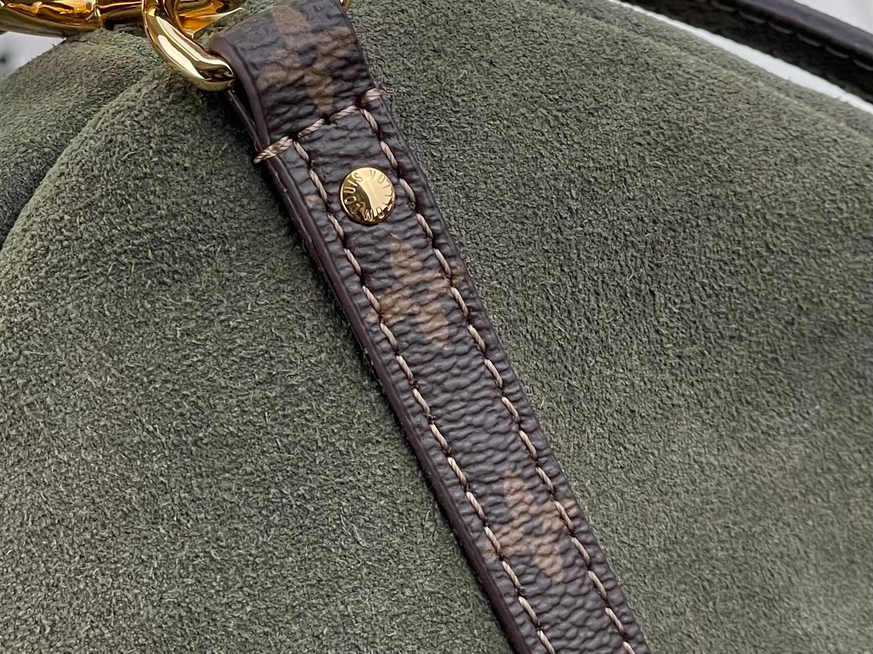Louis Vuitton strap end detail: brown monogram tab with stitched border on olive bag