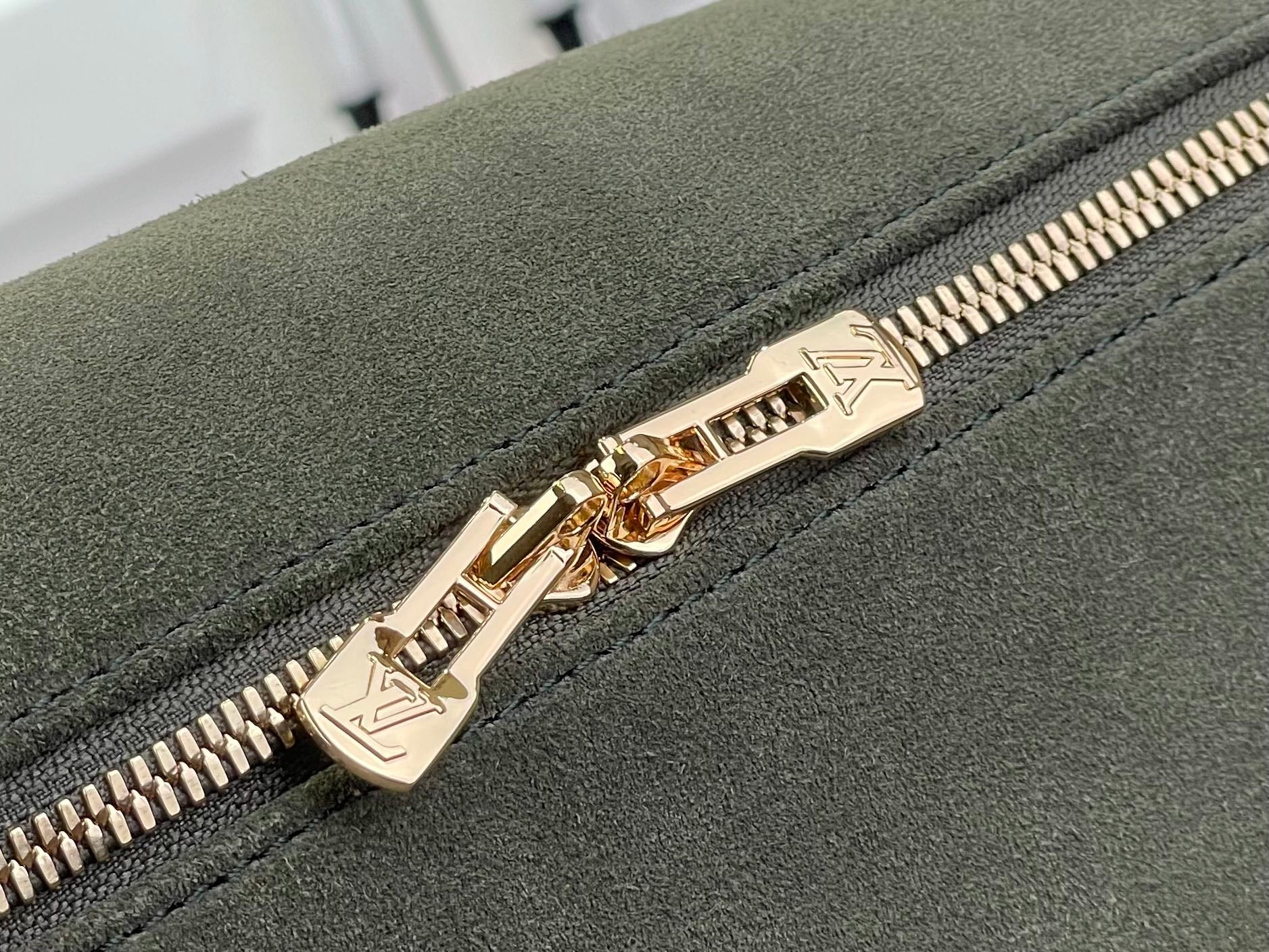 Louis Vuitton gold zipper pull on olive green suede with stitched zipper edge