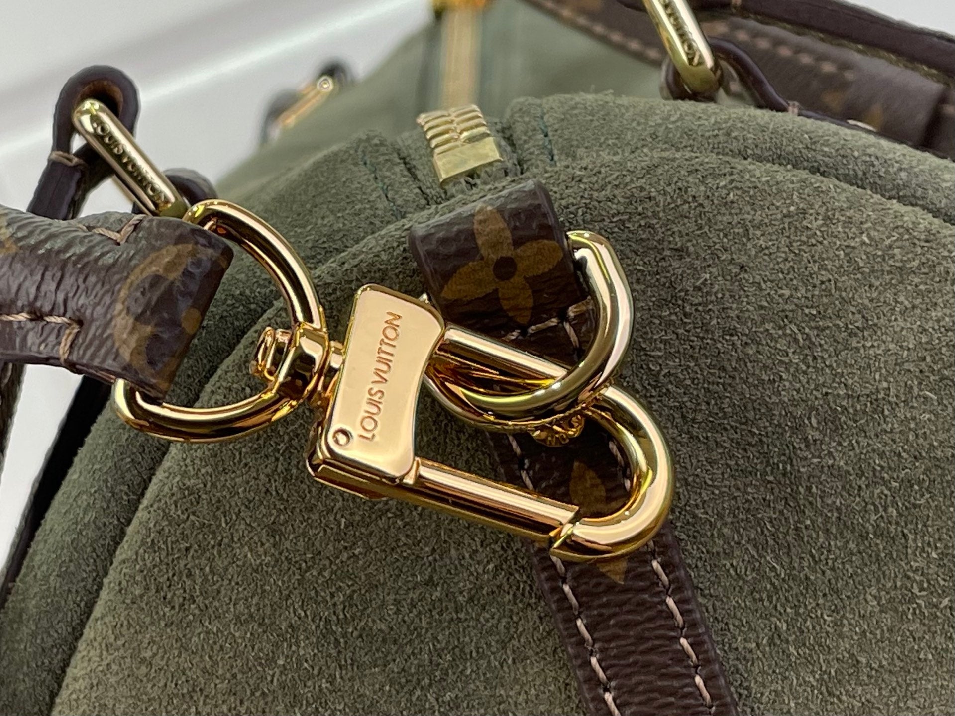 Louis Vuitton clasp detail: gold hook on olive green bag with monogram strap