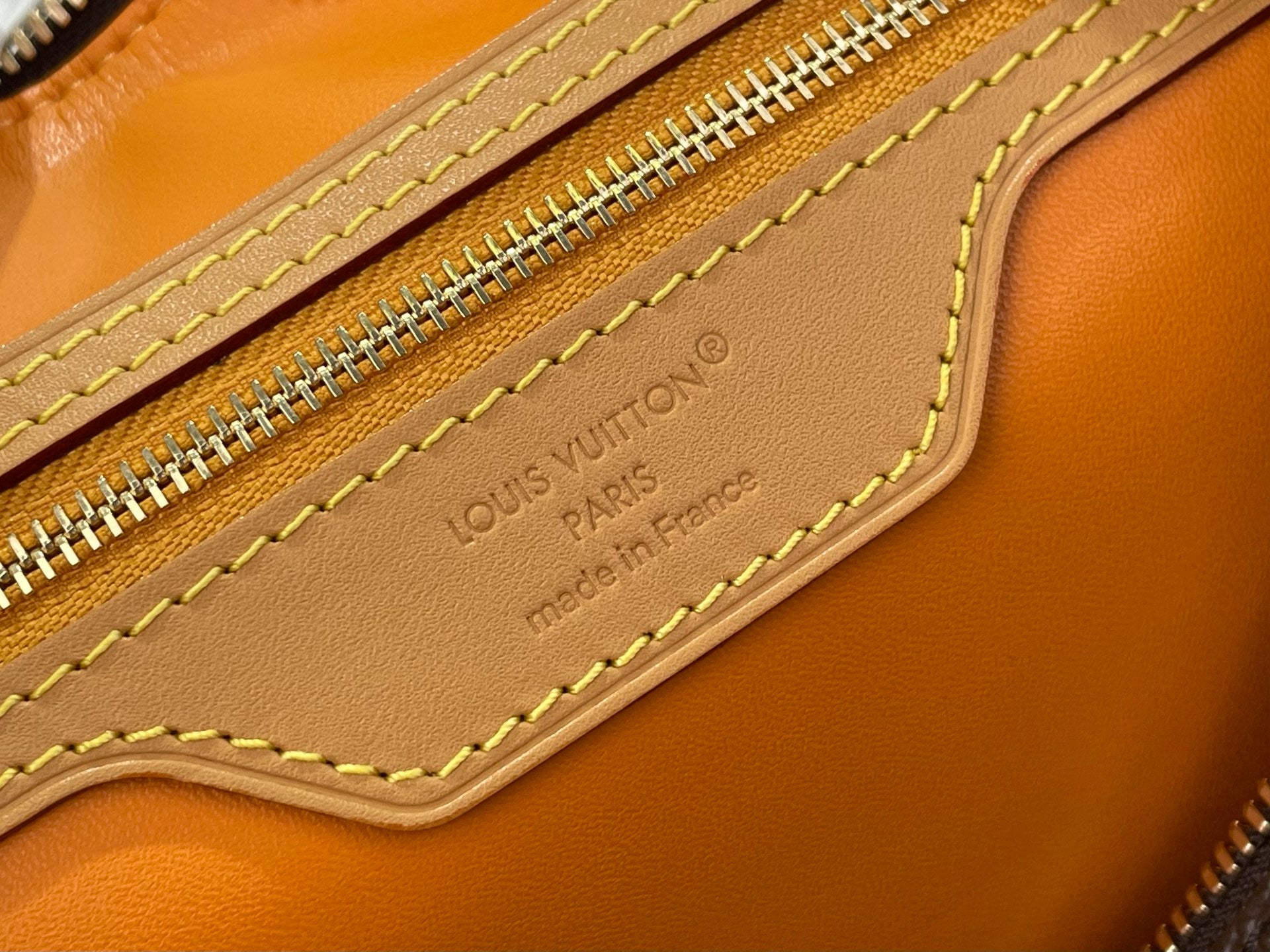 Monogram bag interior label on tan leather with gold zipper and stitching
