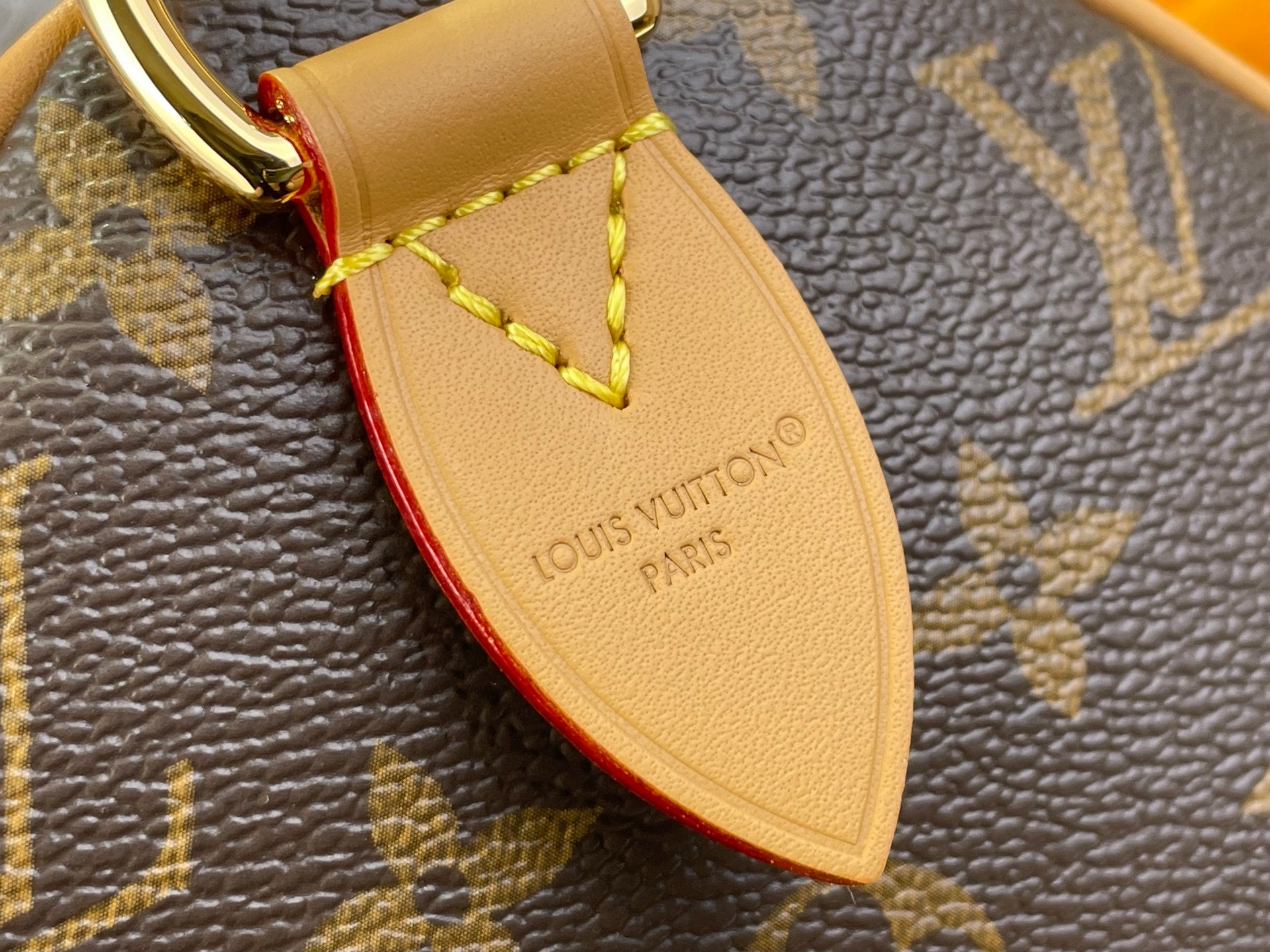 Louis Vuitton leather strap label with red edge trim on monogram handbag