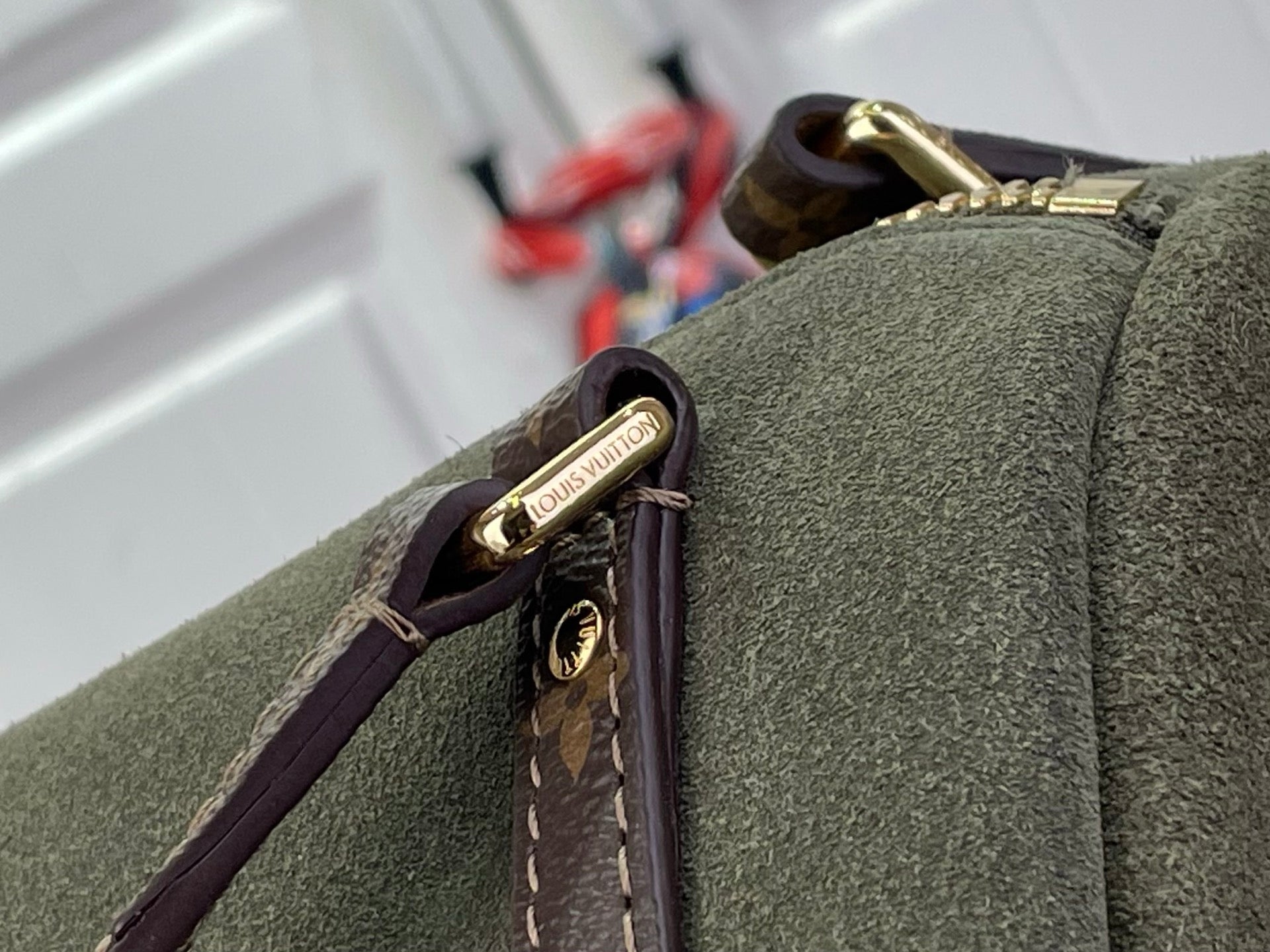 Louis Vuitton logo hardware tag on olive green bag edge with brown monogram strap