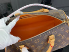 Monogram bag with open orange lining and gold zipper, tan handles