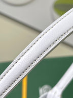 White leather strap edge with visible stitching on a light blue monogram bag
