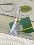 Light blue-and-white monogram hobo bag with long white handles and hanging yellow tag