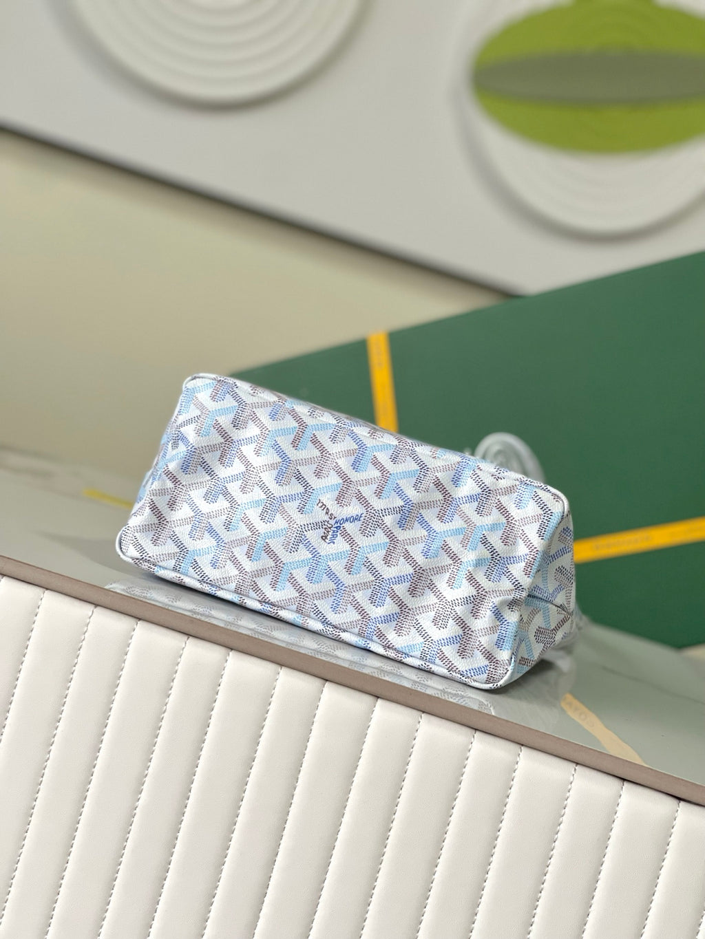 Folded view of light blue monogram clutch-style bag with top flap and handle
