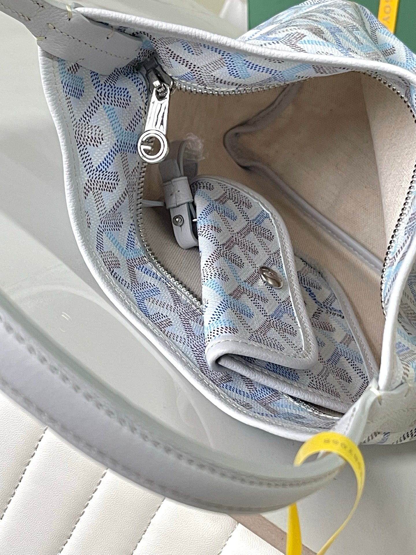 Open interior of light blue monogram bag with side pocket and zipper pull ring
