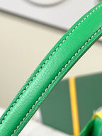 Green leather handle strap with stitched seam on a patterned bag.