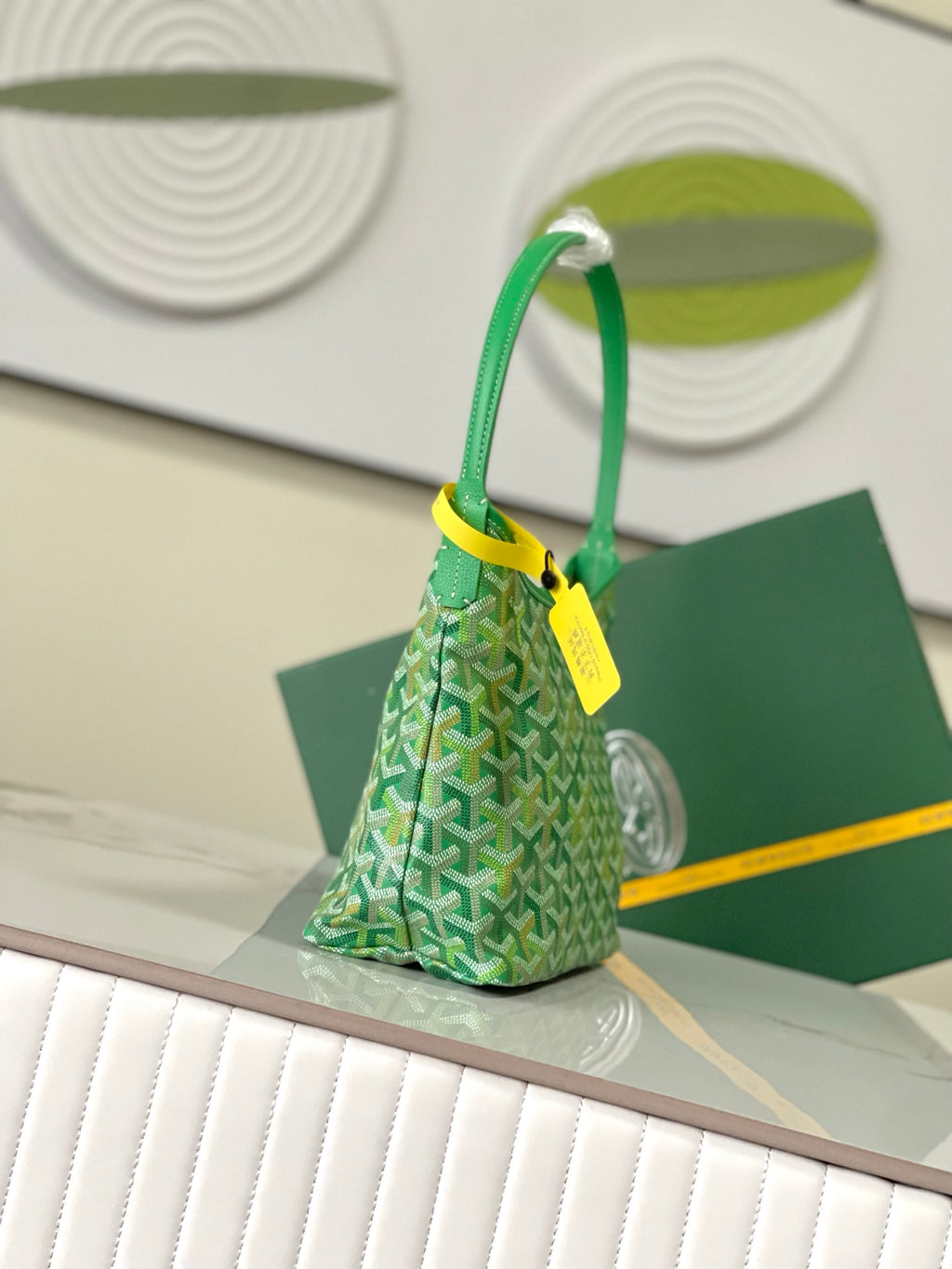 Green patterned shoulder bag with rounded top handles and yellow hang tag.