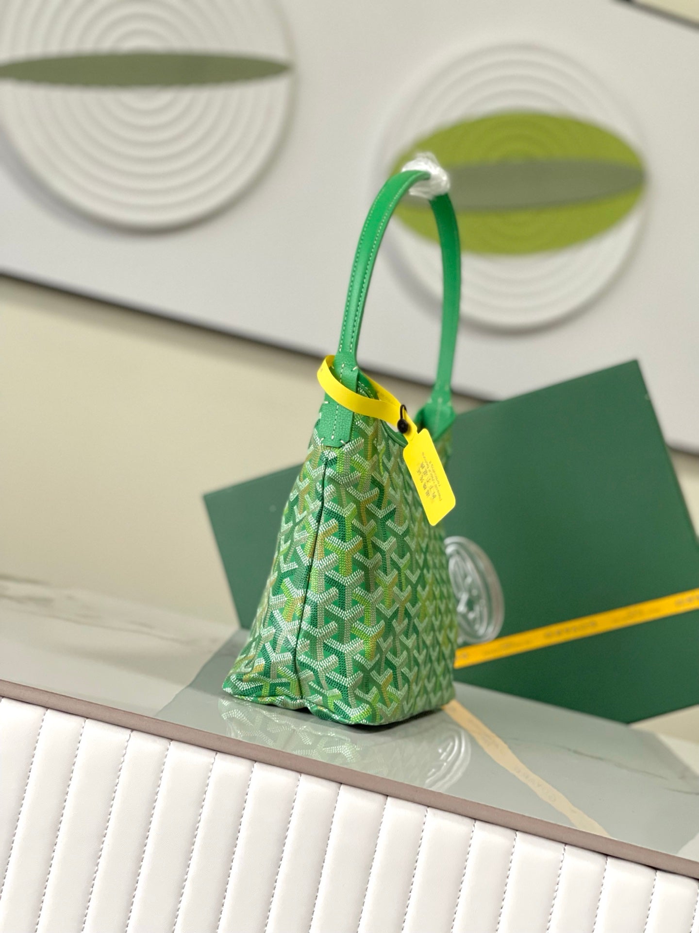 Green patterned shoulder bag with rounded top handles and yellow hang tag.
