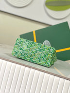 Green patterned bag with top handle and structured shape, displayed on a surface.