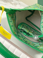Green patterned bag interior with zip pocket, straps, and metal hardware.