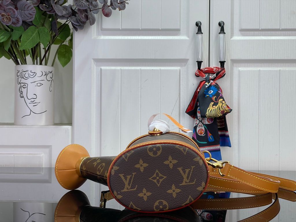 Louis Vuitton monogram bucket bag with tan top handle and crossbody strap, close-up