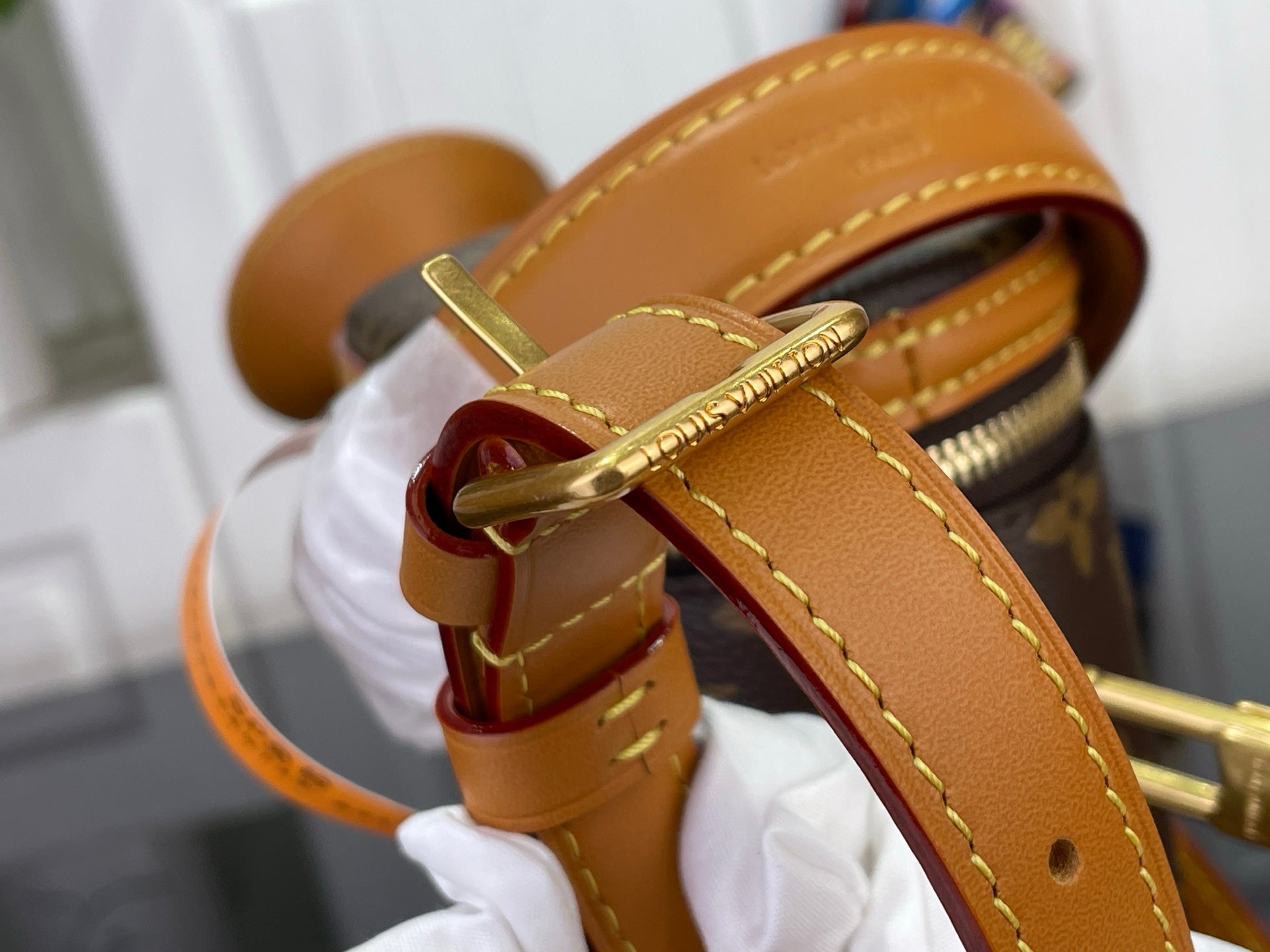 Tan leather strap with gold buckle on Louis Vuitton monogram bucket bag