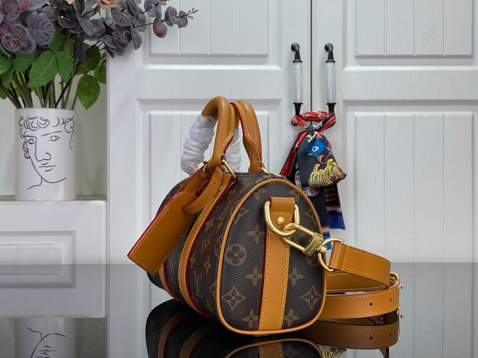 Monogram canvas duffel bag with tan leather shoulder strap and side handle