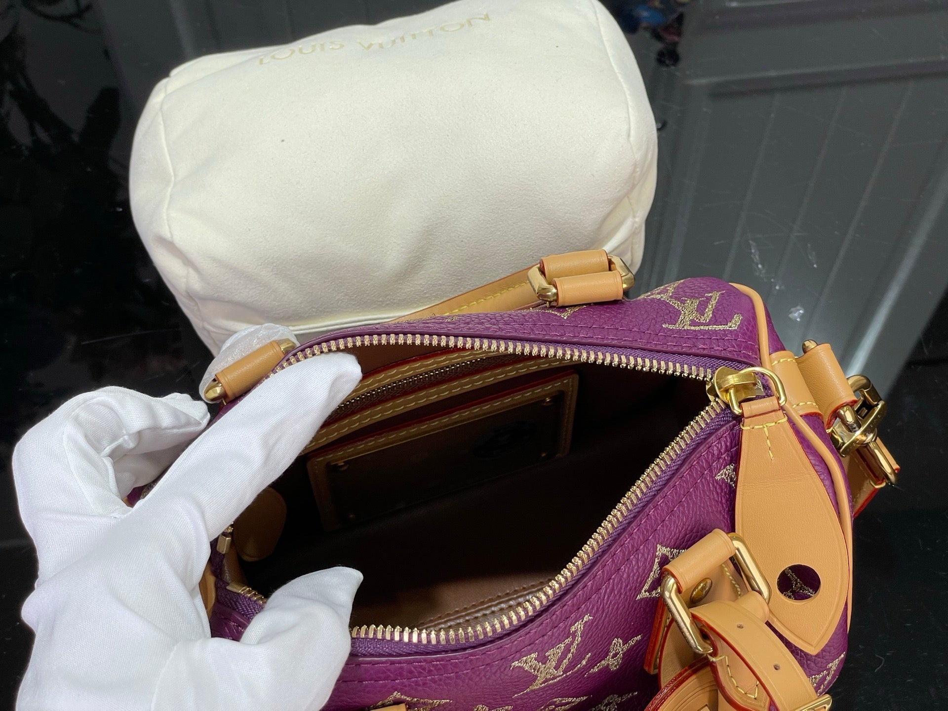 Louis Vuitton monogram bag open, brown interior and gold zipper on purple