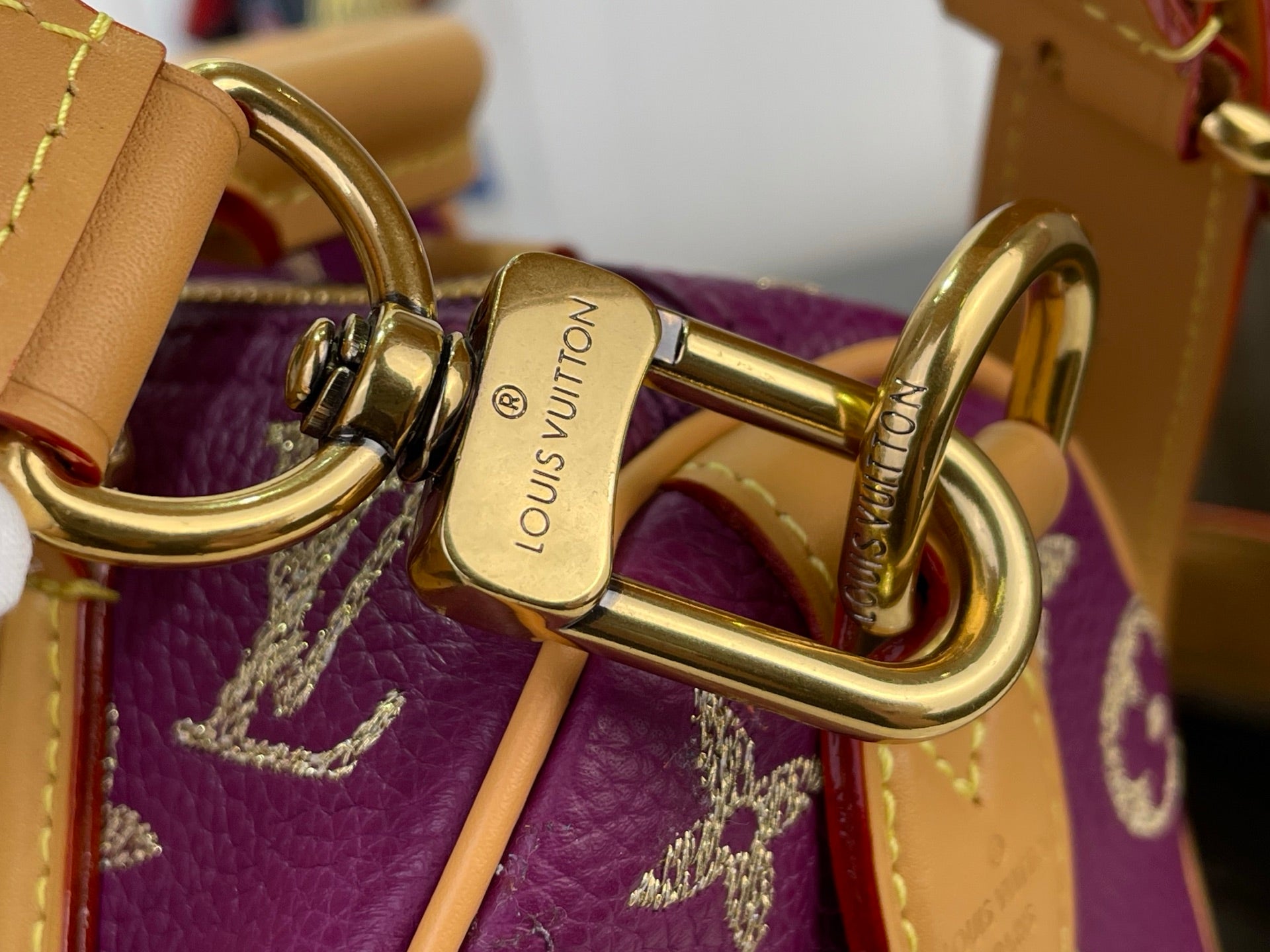 Louis Vuitton purple monogram handbag close-up of gold-tone clasp and tan hardware