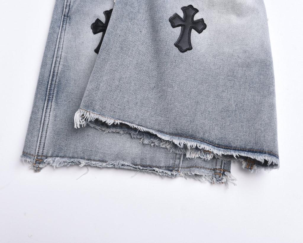 Light-wash denim shorts with frayed distressed hem and cross appliqués