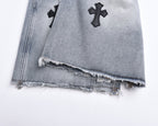 Light-wash denim shorts with frayed distressed hem and cross appliqués