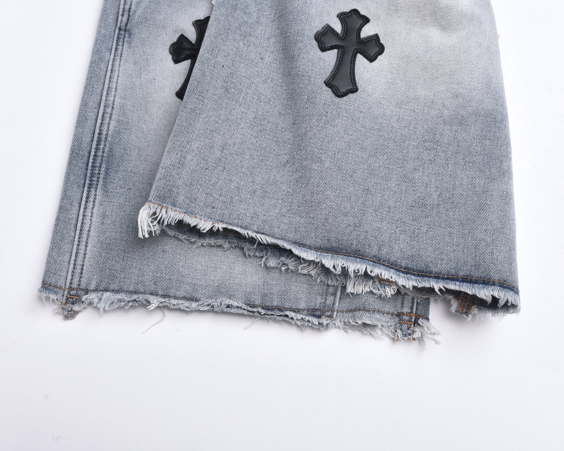Light-wash denim shorts with frayed distressed hem and cross appliqués