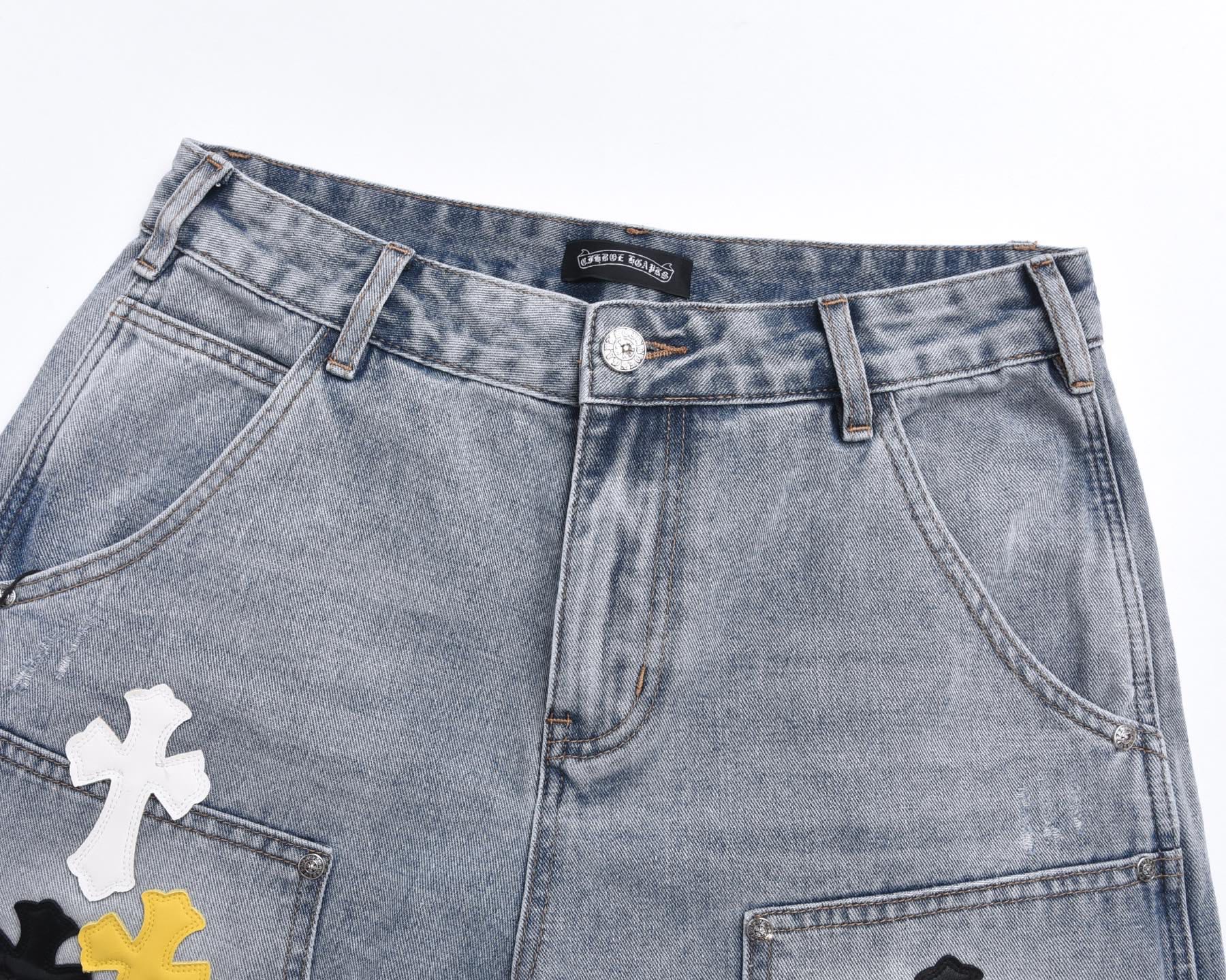 Light-wash denim shorts, front view, with printed cross patches and button fly