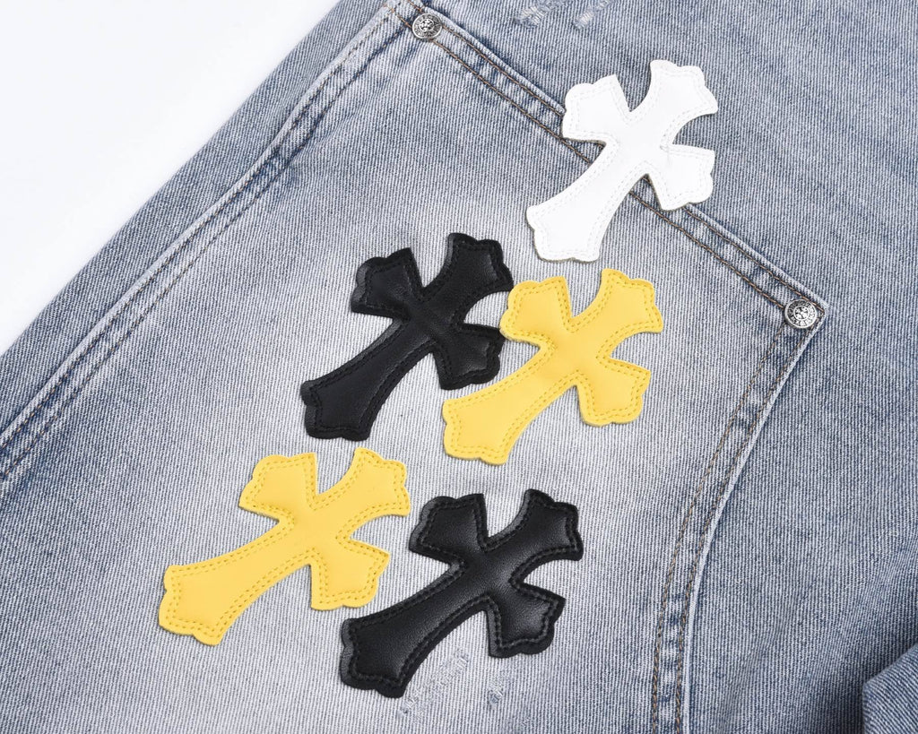 Light-wash denim shorts with close-up cross patches in white, black, and yellow