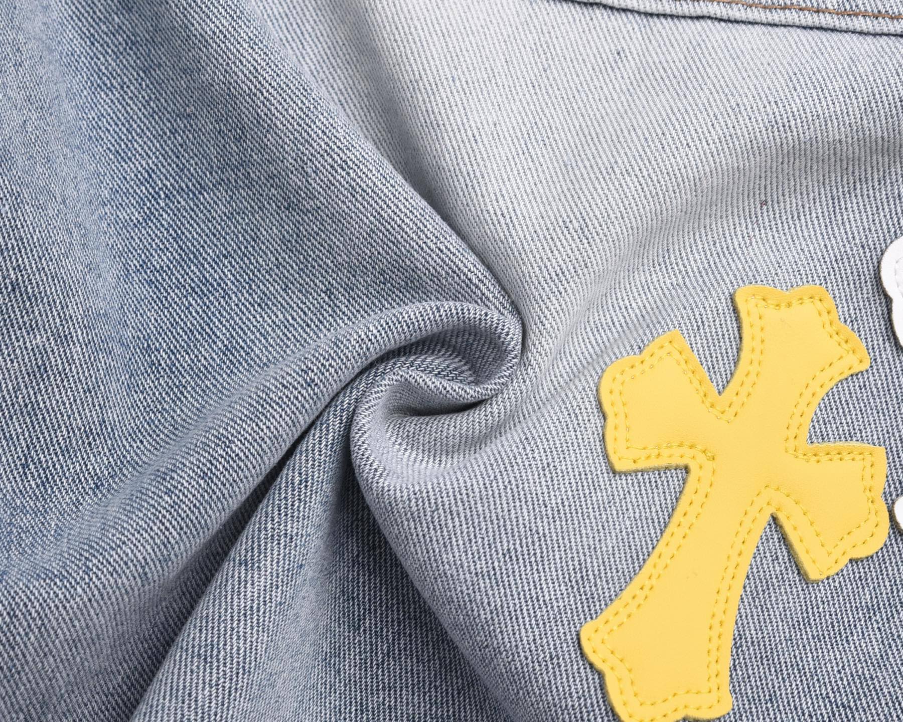 Light-wash denim fabric with yellow cross patch appliqué