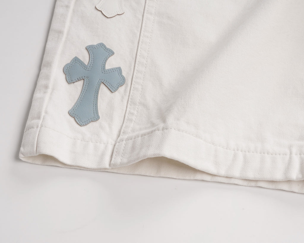White shorts hem with blue cross patch appliqué