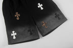 Black shorts with cross appliques along the hem, side-by-side leg view
